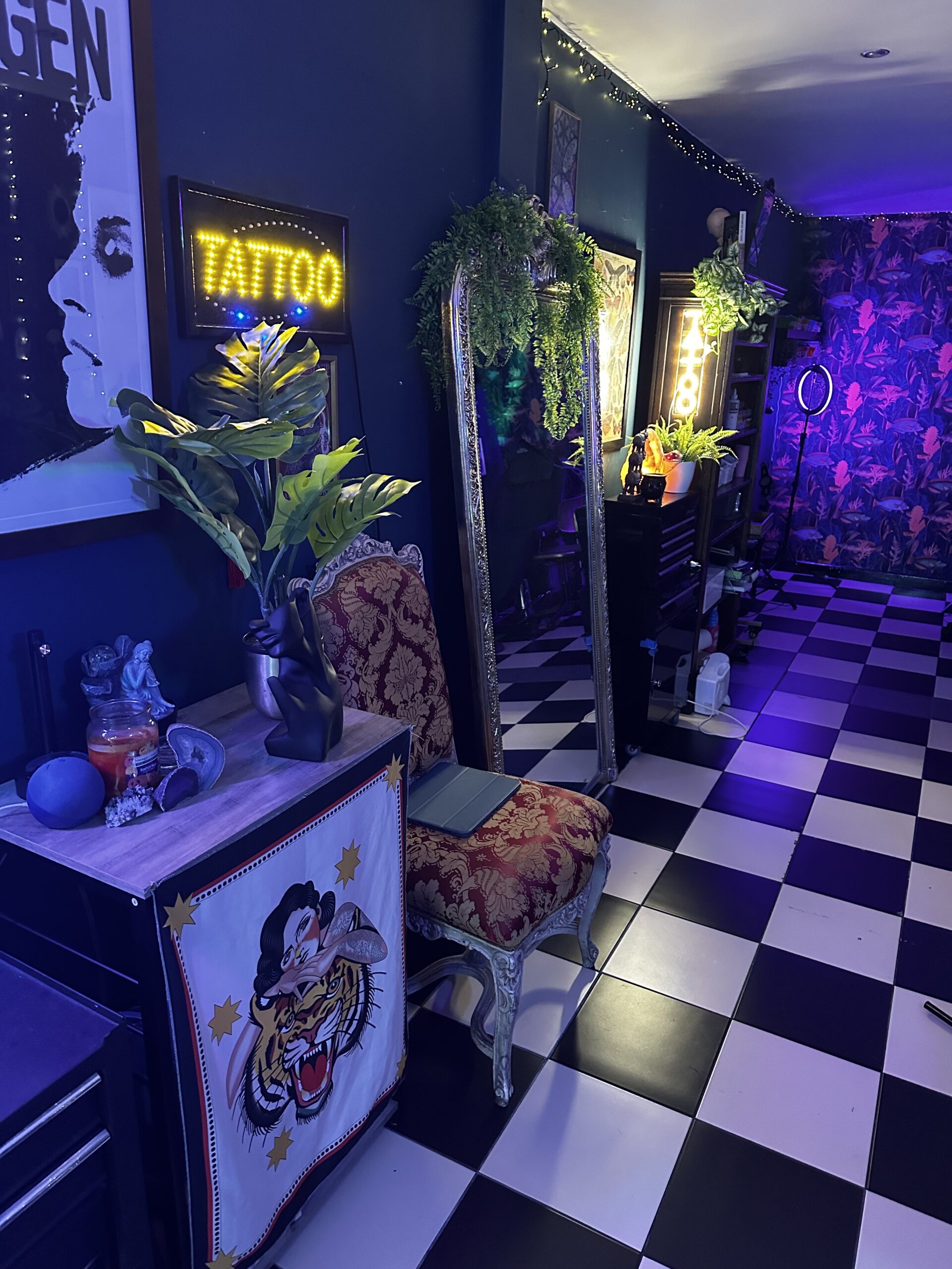 Image of a client waiting area at Ashton Ink Tattoo Studio, with several neon tattoo signs in the shot